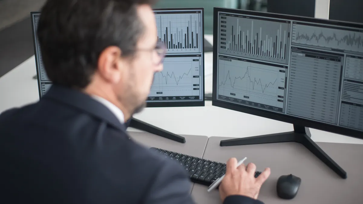 Man viewing analytics charts on dual monitors