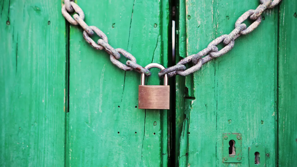 Padlock and chain securing green doors