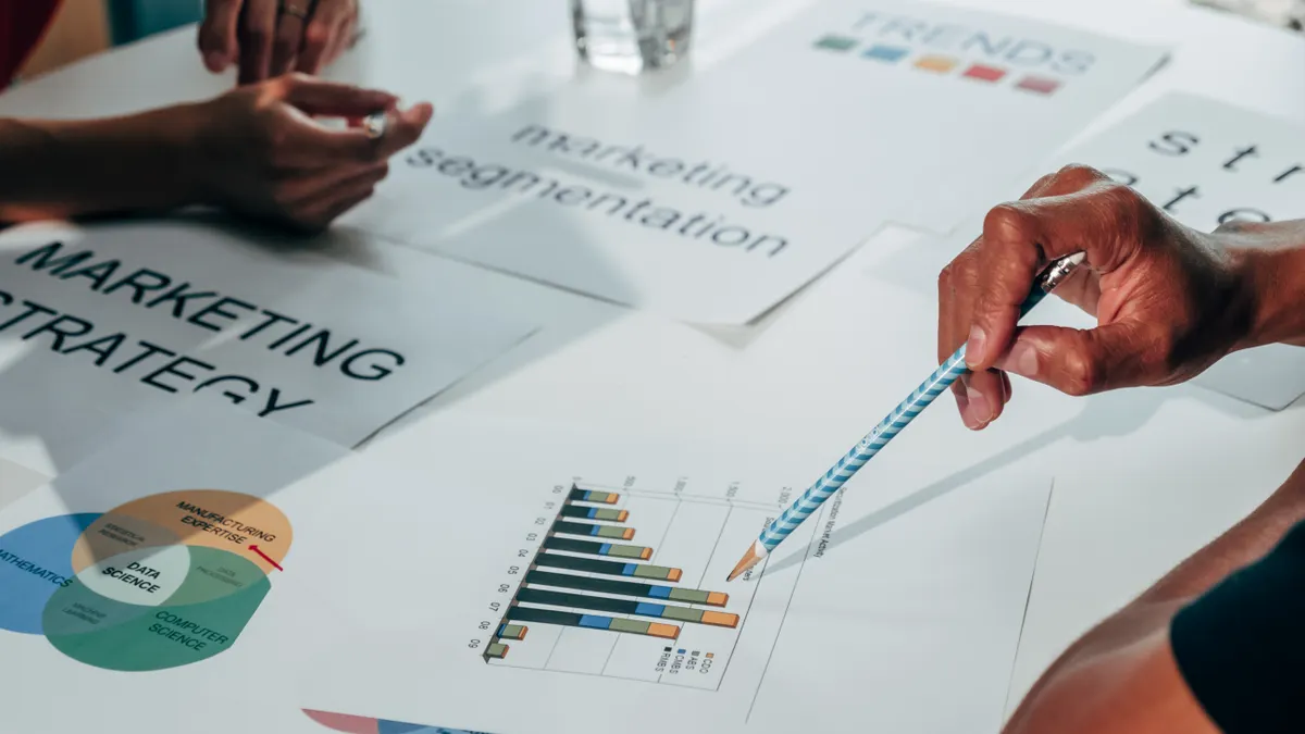 SaaS product intelligence from public signals — The Complete Guide Hands discussing printed marketing charts and graphs
