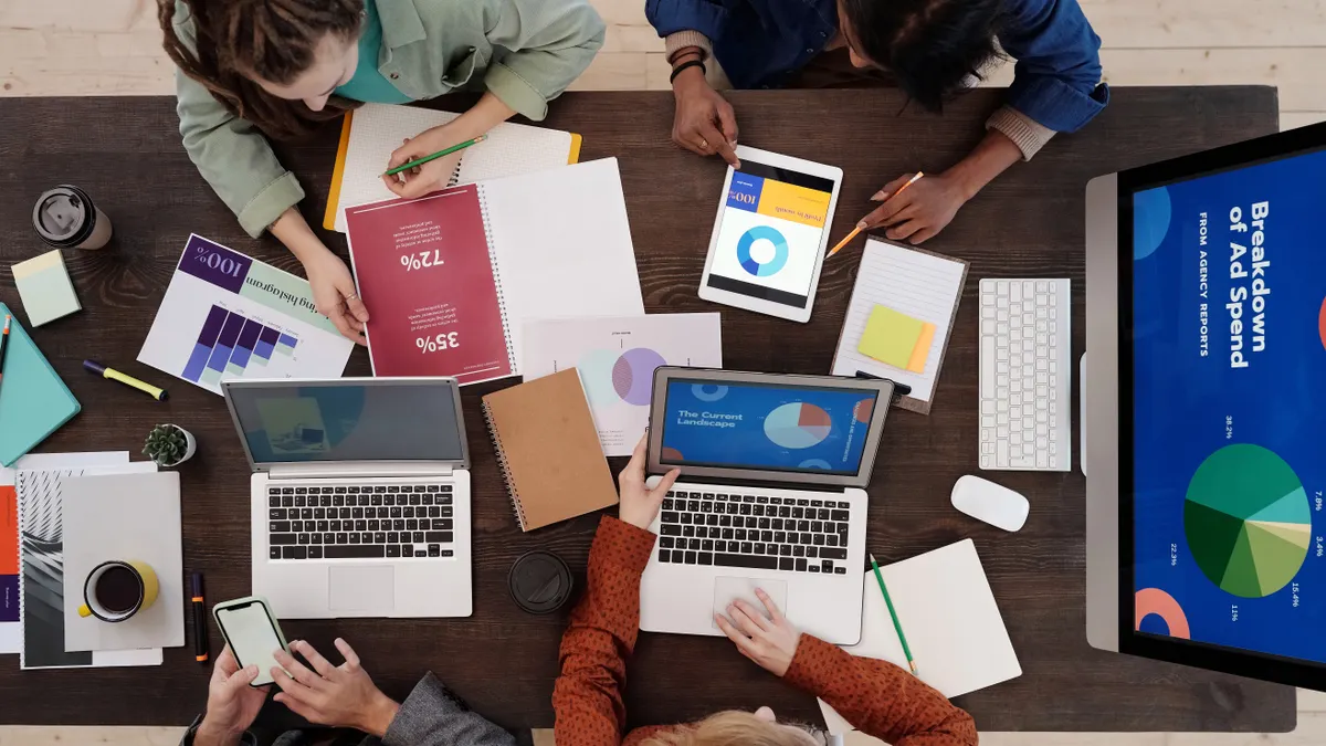 Overhead team desk with laptops and analytics dashboards